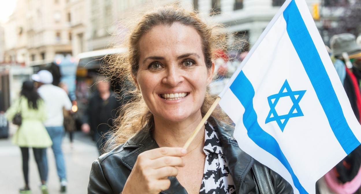 A woman holding a small Israeli flag in a crowd