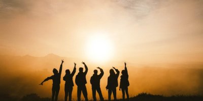 Six teens with their backs to the camera looking out at horizon giving peace signs