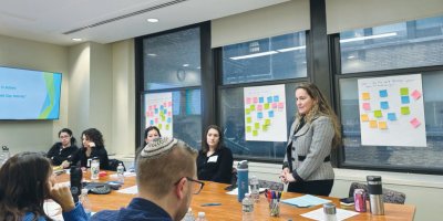An educator standing before a room of educators at a table