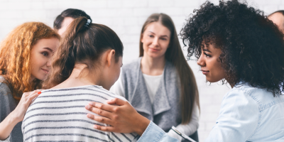 a group of adults comfort someone in group therapy