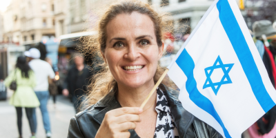 A woman holding a small Israeli flag in a crowd