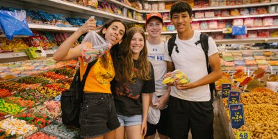 Four teens in the shuk (market) holding bags of Israeli gummy candies