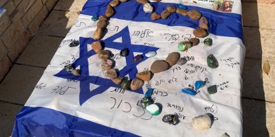 an Israeli flag and rocks cover a gravestone