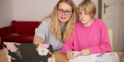 A mom with her pre-teen daughter looking at a laptop