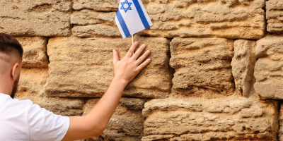 A man holds a small Israeli flag to the Western Wall