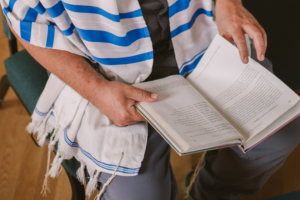someone with a prayer shawl looking down at a prayer book