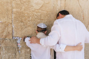a father and son hug at the kotel with backs to the camera