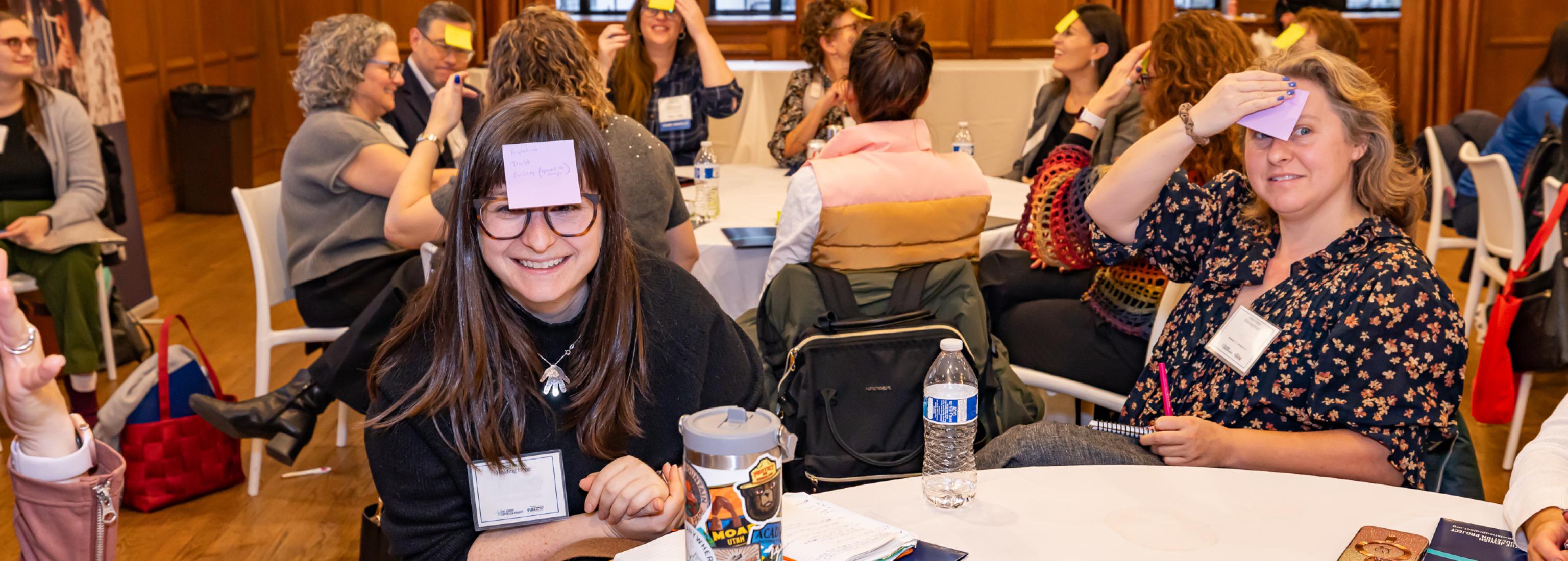 educators sitting at a table have sticky notes on their foreheads