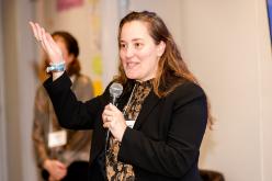 A woman with long hair speaks into a microphone