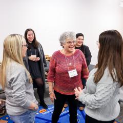 A group of female educators stand in a circle laughing and smiling