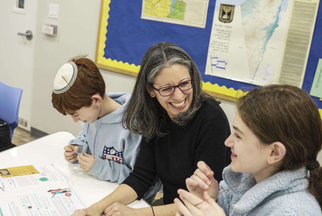 a teacher in a classroom sitting with a girl student
