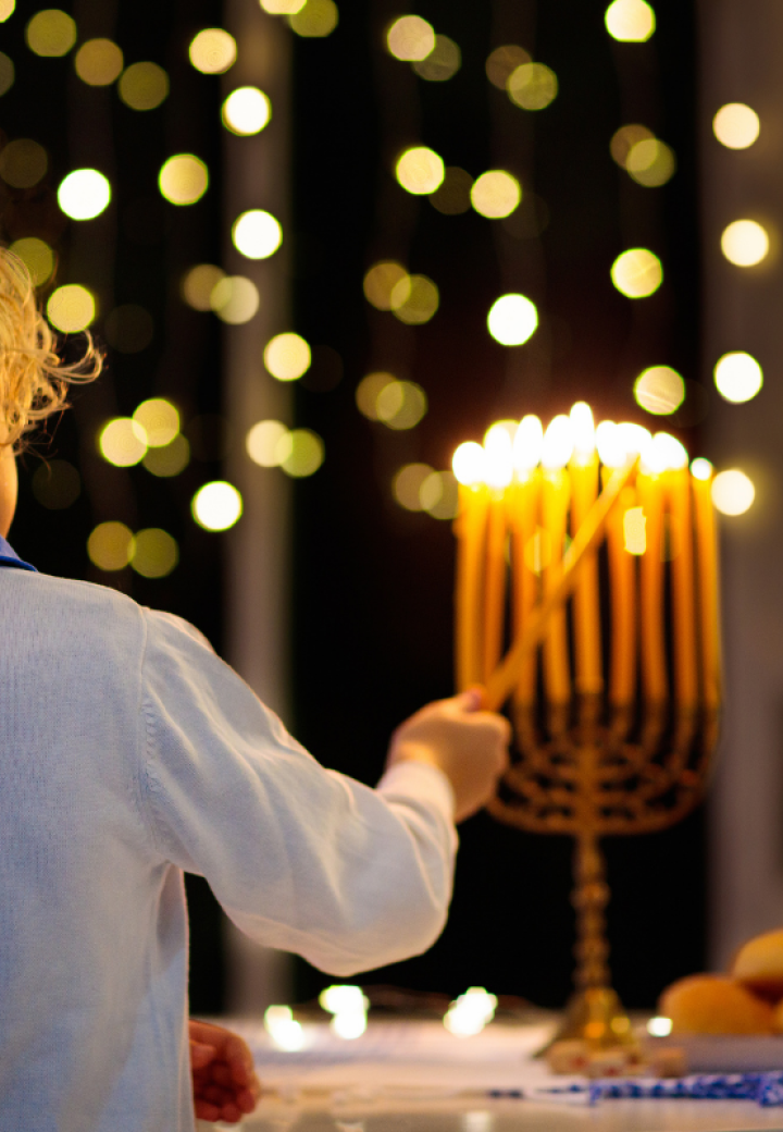 boy with kippah lights a menorah
