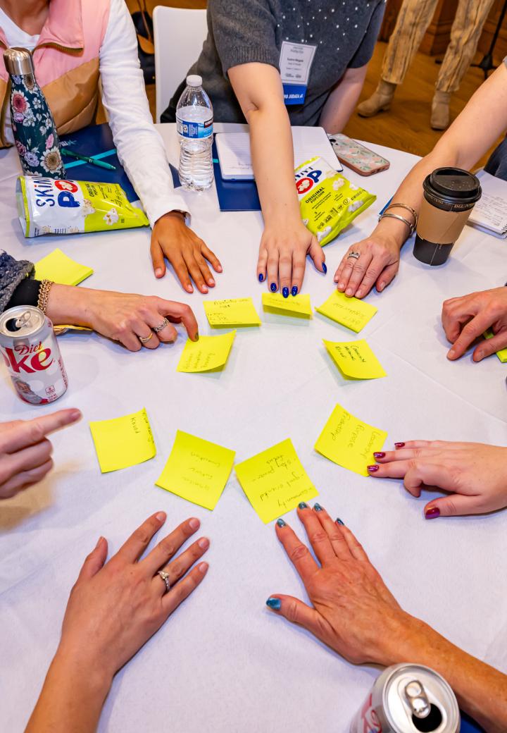 Outstretched arms on a table holding sticky notes with writing on them