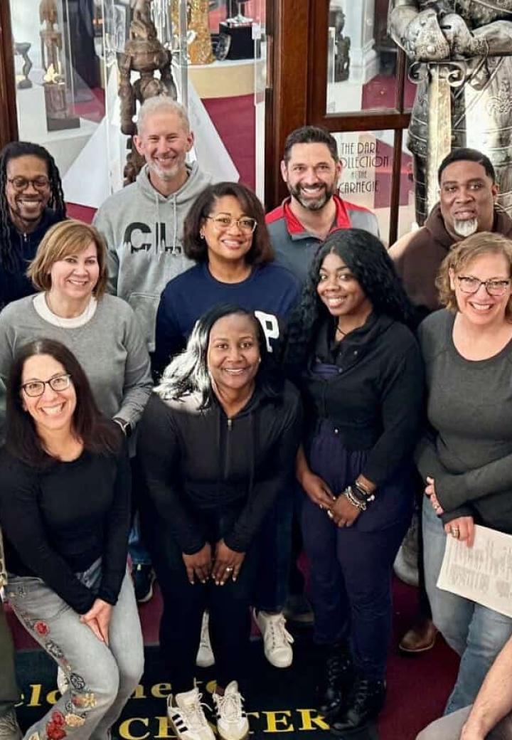 A group of about 13 people pose and smile