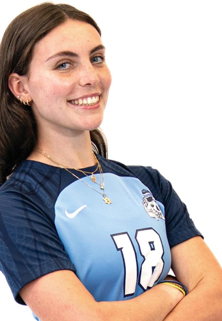 A girl with her arms crossed smiling against a white background