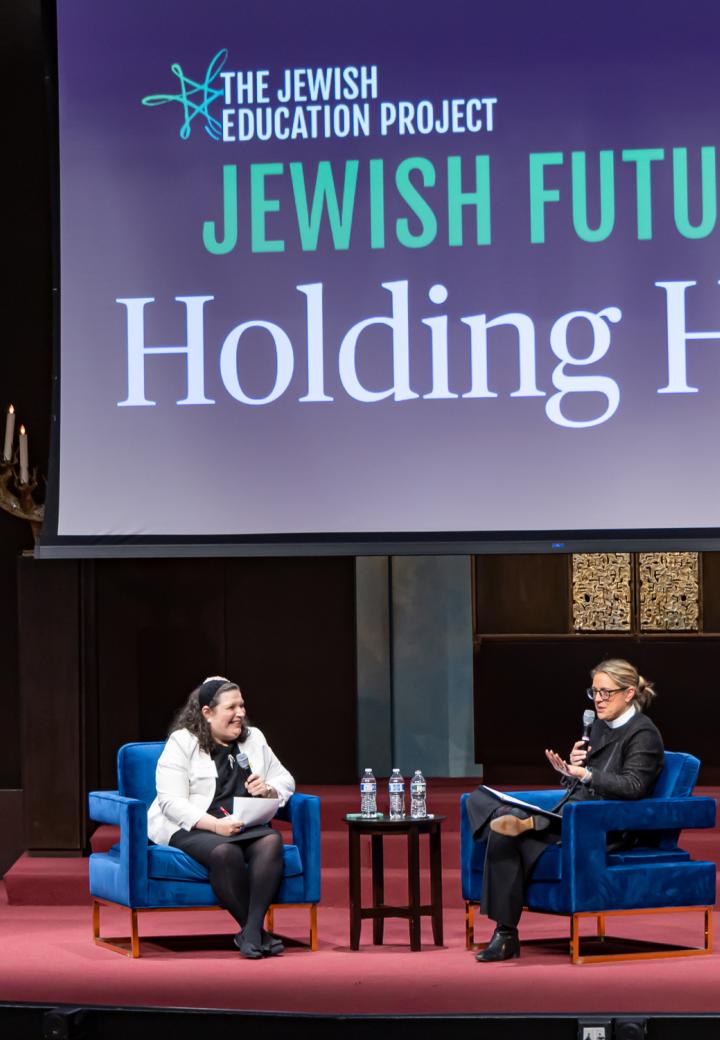two speakers on stage sitting in chairs