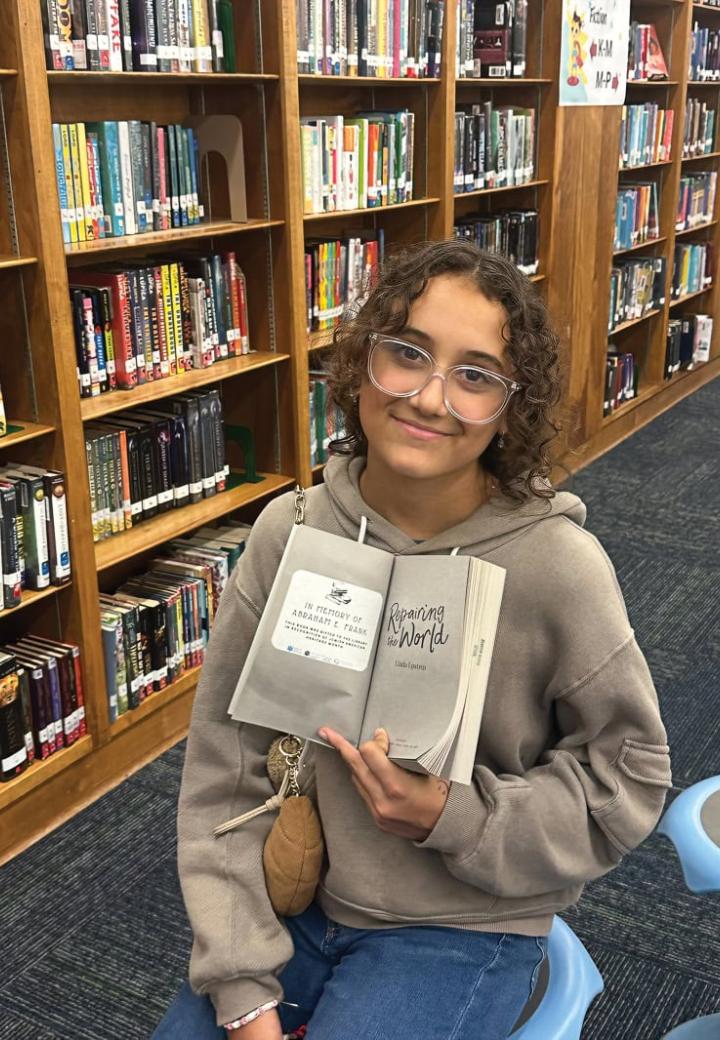 a girl holds a book in a school library