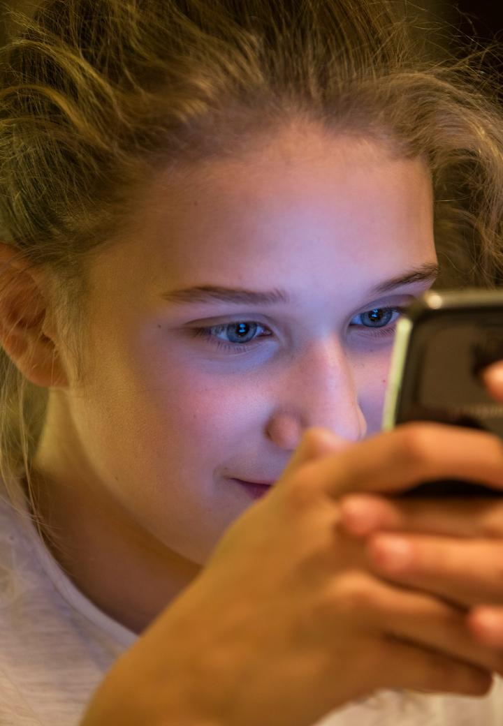 teen girl smiling while looking at a cellphone