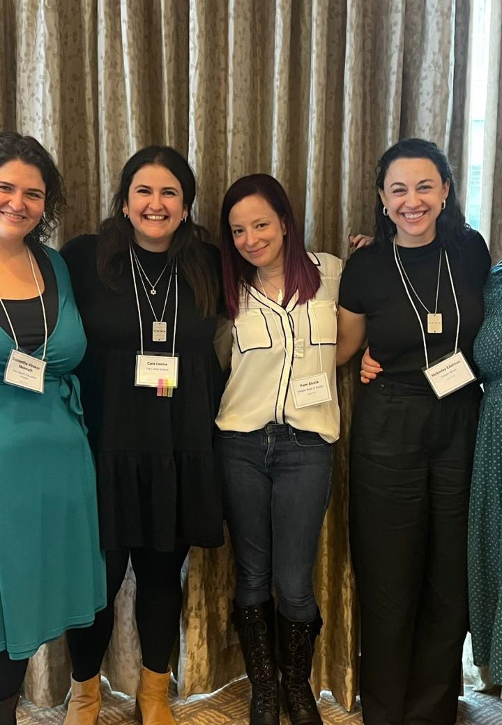 A group of five female educators pose and smile with nametags