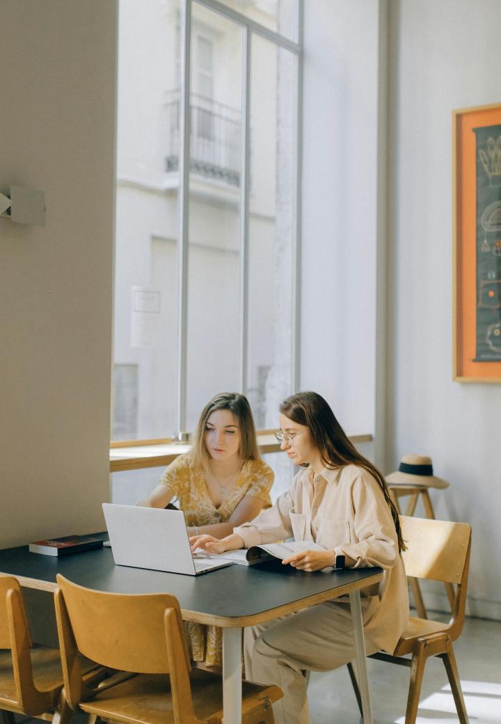 two teens look at laptop in a classroom