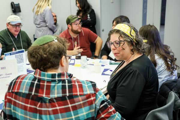 A woman talks to a man with a kippa at a table