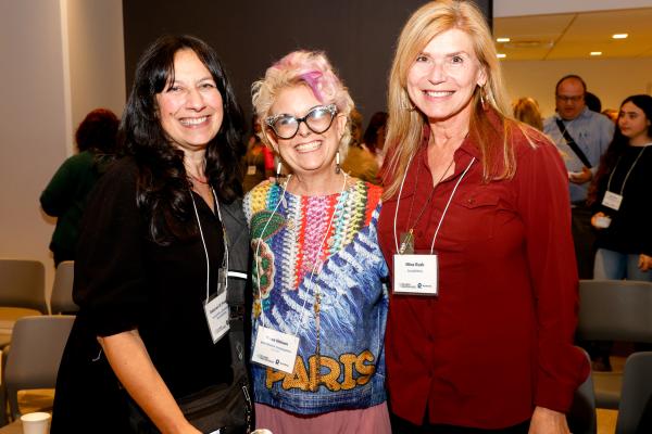three women pose and smile at the camera
