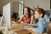 A woman teaches her son as they sit at a computer